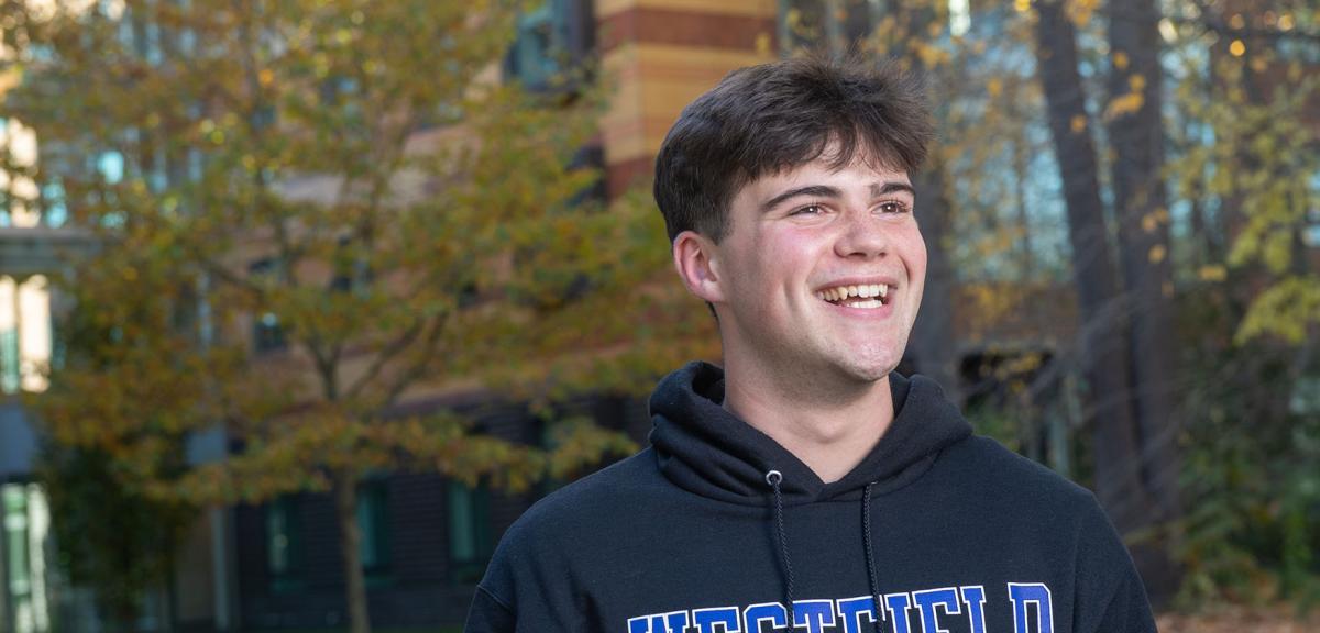 A Westfield State University student smiles as they walk across campus.