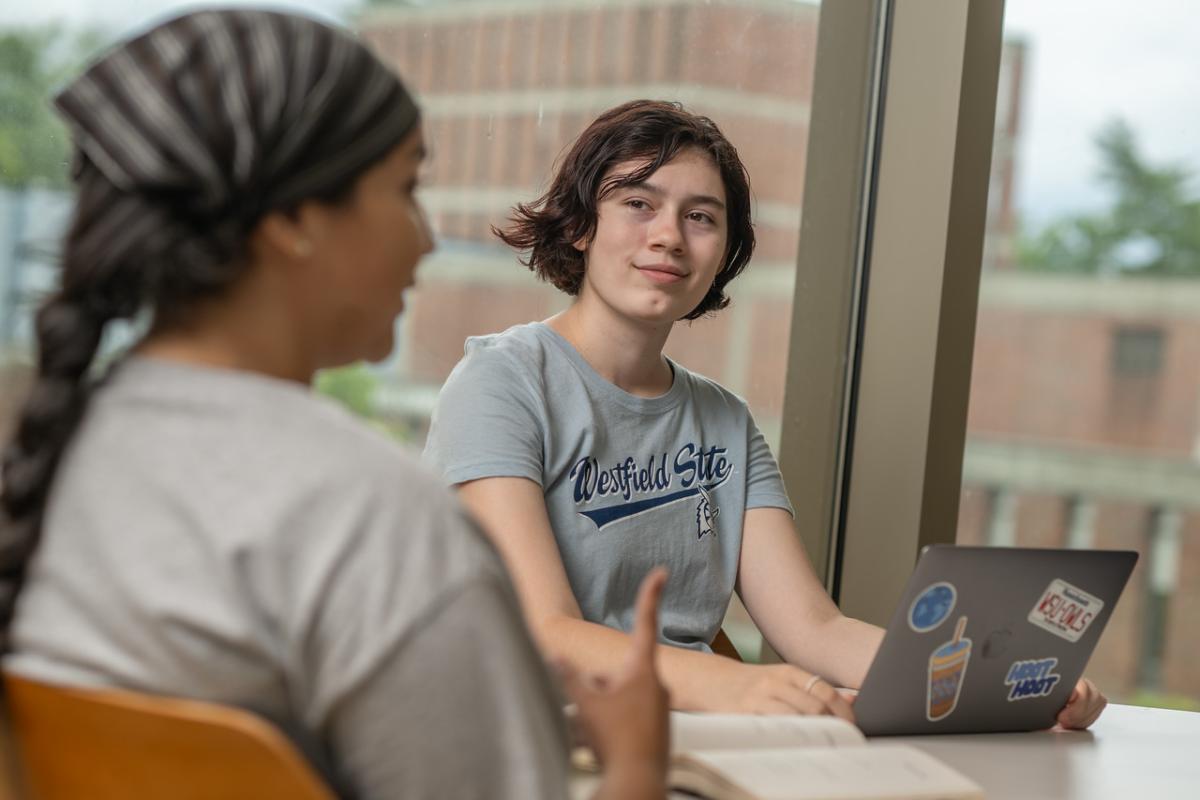 English student smiling with a laptop wearing a WSU shirt.