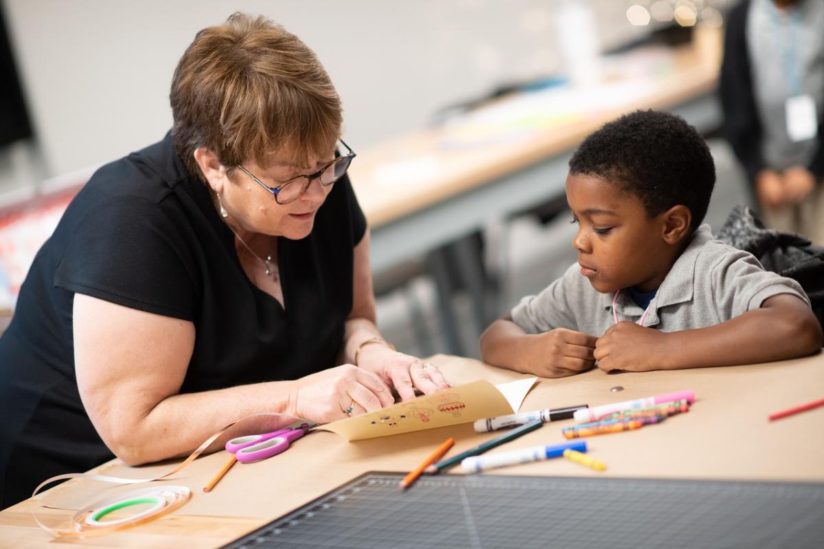 Faculty member and student at a table coloring with crayons and markers.