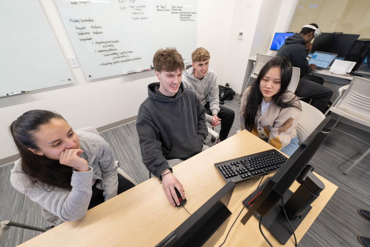 Team of students work together collaboratively in a finance lab.