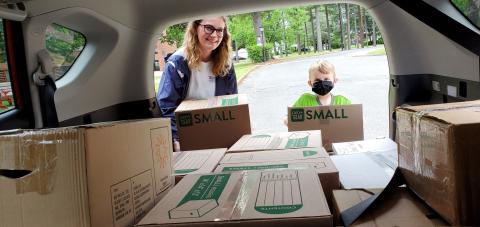 Photo of volunteers taking boxes of donations out of a car