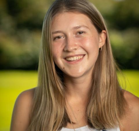 Student tour guide Shea Hamel. She is smiling and standing in an open field, with the background blurred behind her. 