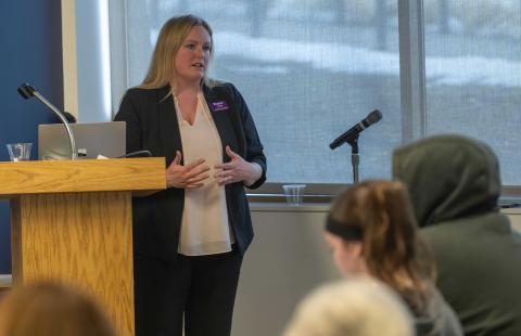 Woman stands at podium speaking to an audience