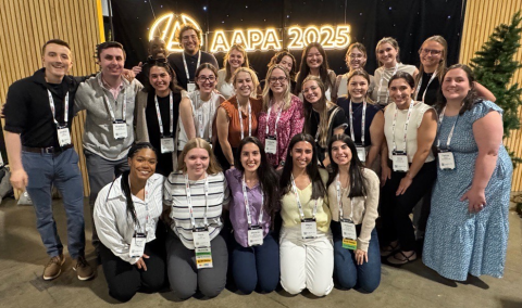Students stand in a group in front of logo for AAPA 2025 Conference