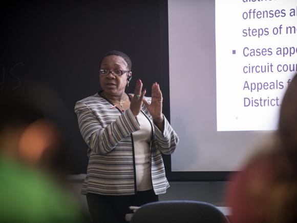 CJ professor lecturing in class in front of a projection screen