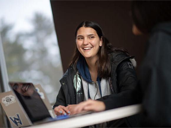  A student smiles while working on their laptop.