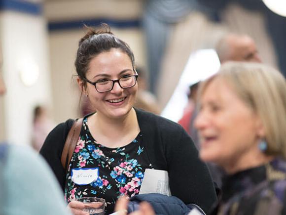 A student smiles while engaging in conversation in a group.