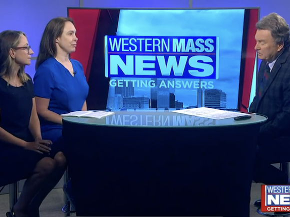 A still-image of three people sitting around a round table. From left to right: Jessica Holden, Sarah Warn, and their interviewer.