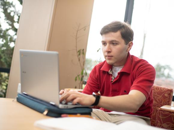 ABA student studying in library with laptop