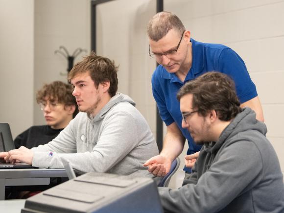 CIS student being helped by a faculty member in classroom.