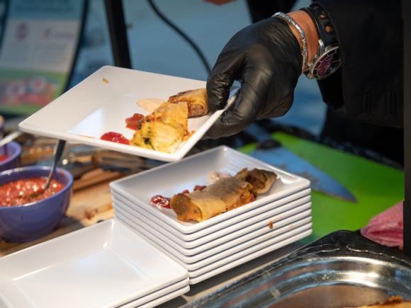 A close-up shot of Chef Ming from the Iron Chef at the University's annual fall food show. There's a stack of white, square plates, and homemade bings on them, which are Chinese streetfood crepes.