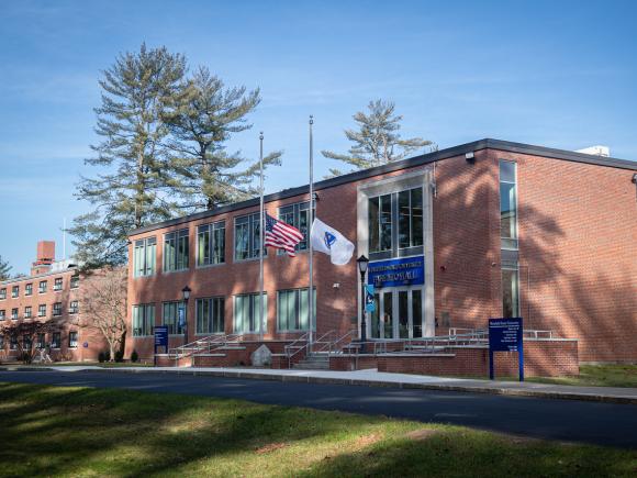 Exterior of Parenzo Hall with two flags flying in front and blue skies in the background.