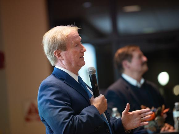 James Hagan lecture with him wearing suit holding a microphone.