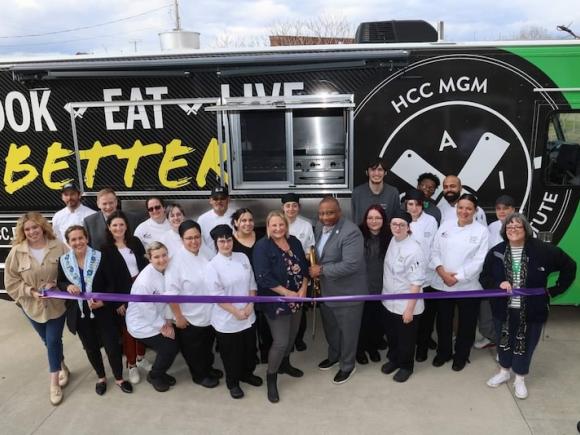 A food truck at Holyoke as part of their initiative to promote healthy eating. Stacy Graves '05, Facility Coordinator for the Culinary Arts Institute at Holyoke Community College, stands around a crowd of her students who will be in charge of the truck. 