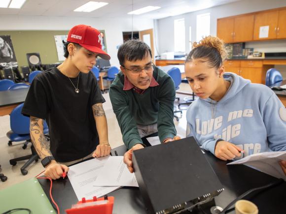 Professor Vaitheeswaran working alongside two students in classroom.