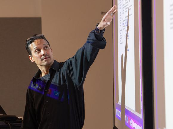 An education professor at Westfield State University motions to information projected on a screen while teaching.