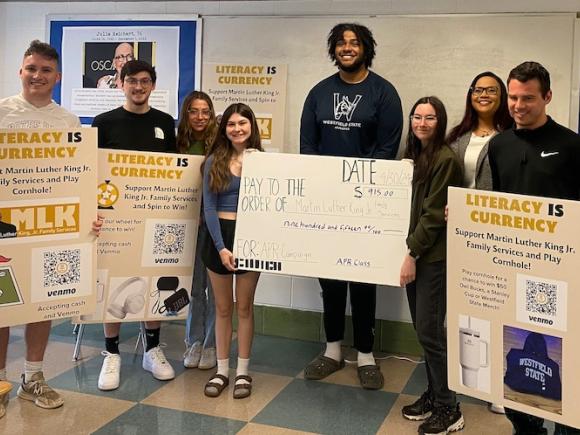 "Students from Westfield State University's "Advanced Public Relations" course pose with Shannon Rudder, executive director and CEO of Martin Luther King Jr. Family Services, and the $915 they raised for the nonprofit. Left to right, Joe Dateo, Matthew Bunszell, Giana Isola, Grace Murray, Alvin Yvon, Alexis Crafts, Rudder, and Brandon Hager." From MassLive's website.