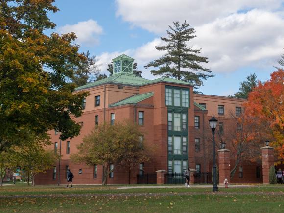 Photo of Courtney Hall with colorful autumn foliage in the courtyard and campus green.