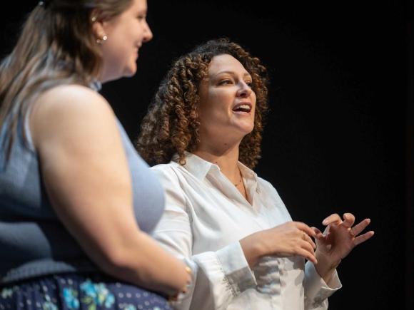 Two women stand on stage and sing