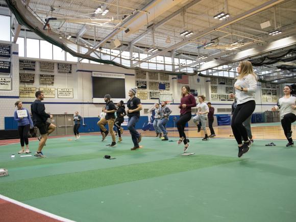 Group of students jumping off a green gymnasium floor