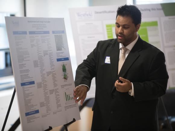 Urban and Regional Planning student giving a presentation pointing to a poster.