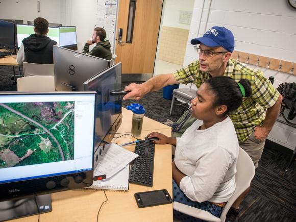 Student and faculty member working on a project together on a computer.