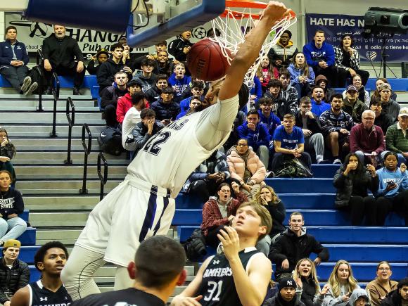 Hamilton dunking the ball at a basketball game, showcasing athleticism and excitement on the court.