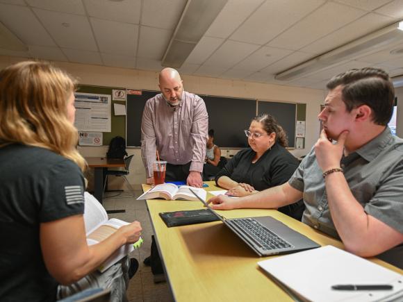 Faculty member engaging in conversation with a group of students.