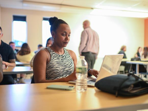 Counseling student in the classroom working on a laptop.