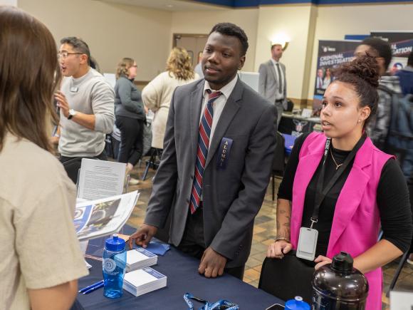 Alum hosting an employer table at the Criminal Justice Career Fair.
