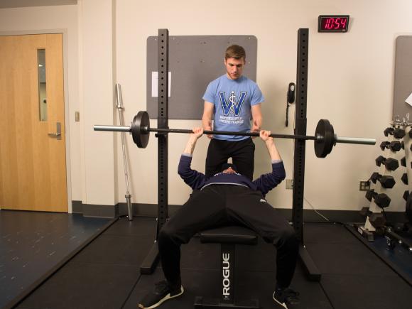 Two students lifting weights in a movement science lab.