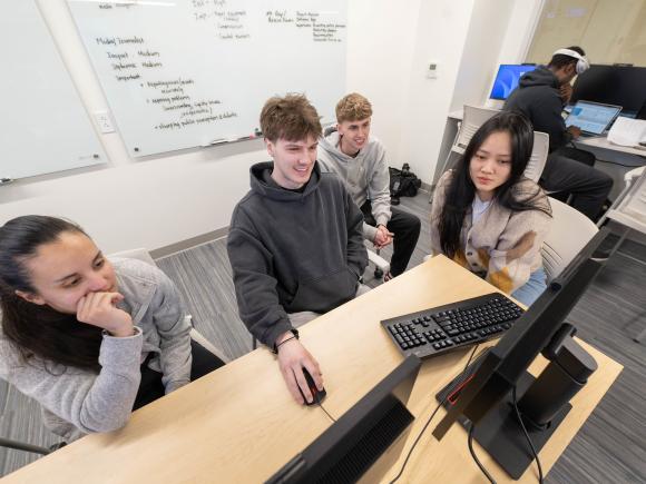 Team of students work together collaboratively in a finance lab.