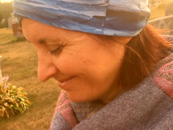 Woman looks down with sun behind her