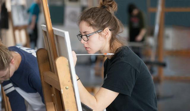 A student works on their painting while in class.