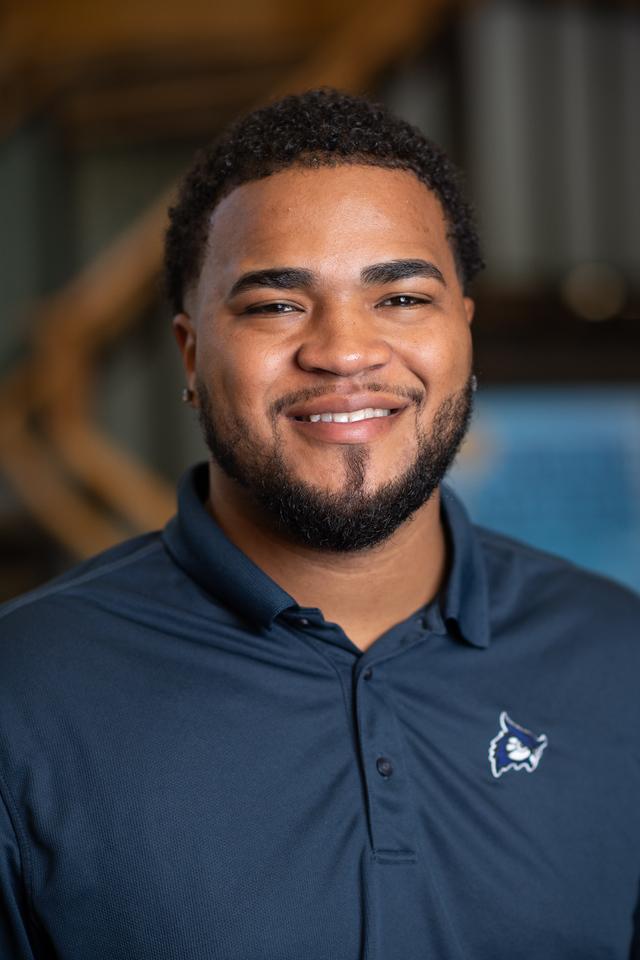 Desmond Admission Counselor smiling with navy blue polo shirt with WSU logo.