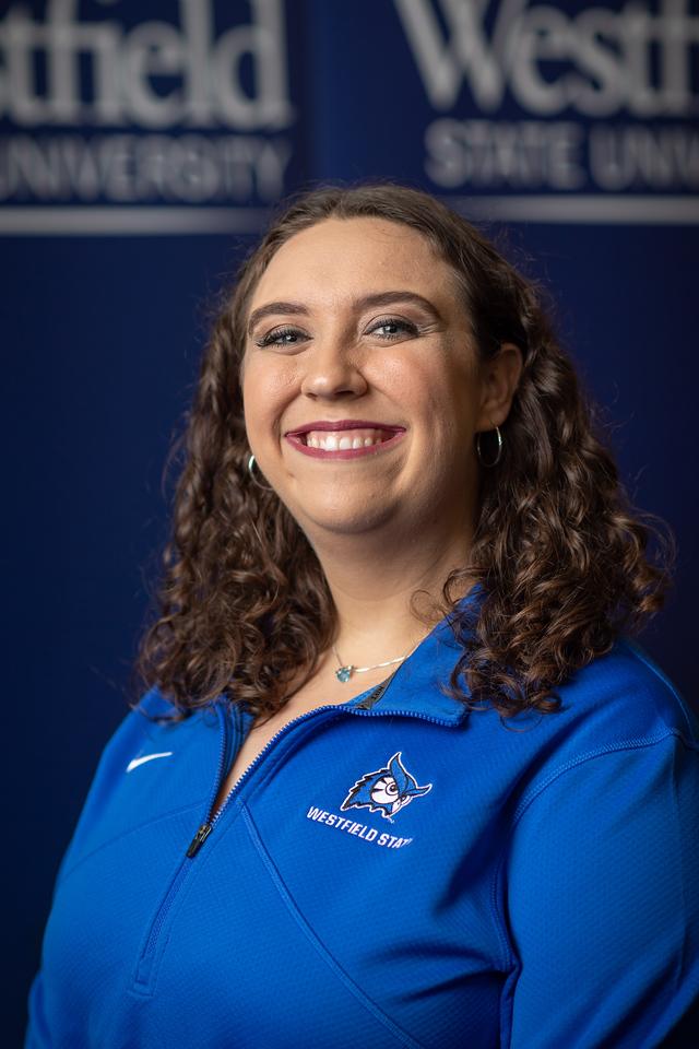 Isabella Admission Counselor wearing light blue polo shirt with WSU logo smiling with curly long hair.