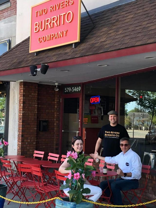 Two Rivers Burrito Company with two people eating outside with server.