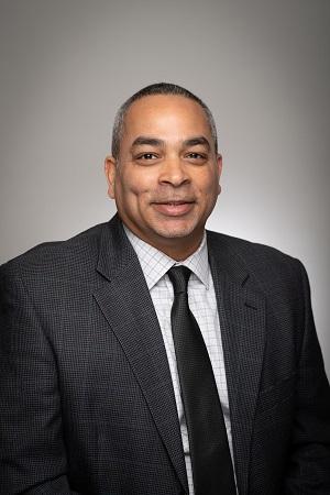 Tyrone, Assistant Director of the LEAD Scholars Program wearing a suit and tie smiling.