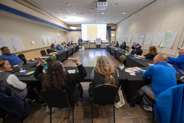 Strategic Planning Visioning Session with members sitting around a large table viewing presentation screen.