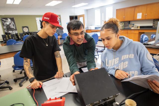 Professor Vaitheeswaran working alongside two students in classroom.