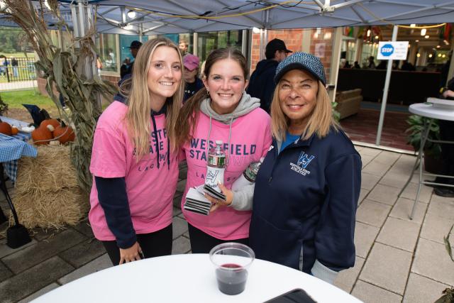 Two students in pink shirts smiling with President Thompson.