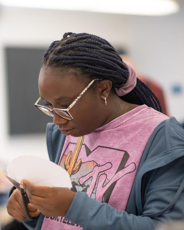 Math student working on a classroom project, using scissors to cut paper.