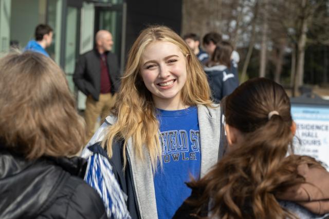 Student smiling and talking to two other students while wearing a Westfield State shirt.