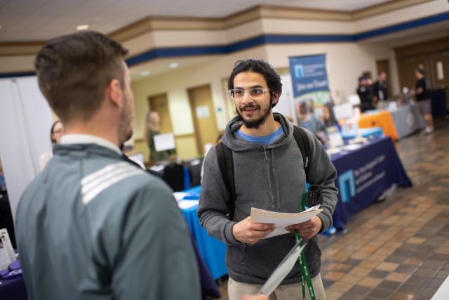 Student talking to an employer at a job and internship fair.