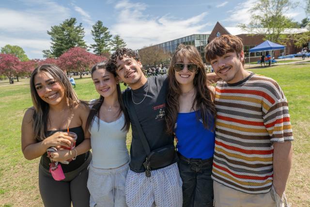 5 Westfield State students smile at the camera on the campus green