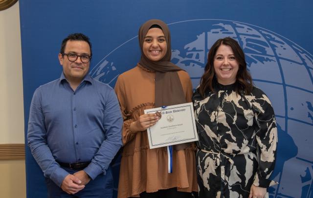 Two Spanish faculty members smiling alongside a student at the Academic Excellence Award Ceremony.