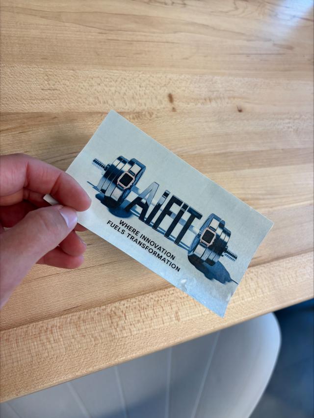 hand holding a rectangular sticker with the workd "aifit" and a dumbbell