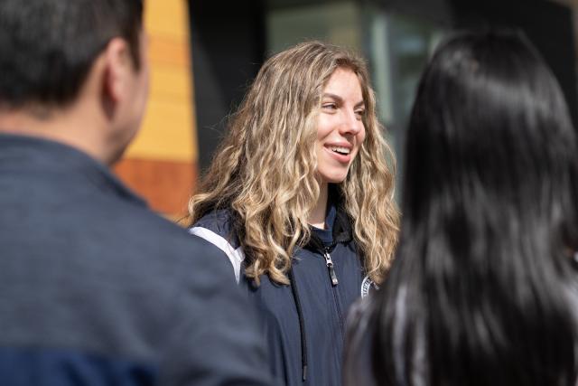 Smiling education student standing outdoors on a sunlit campus.