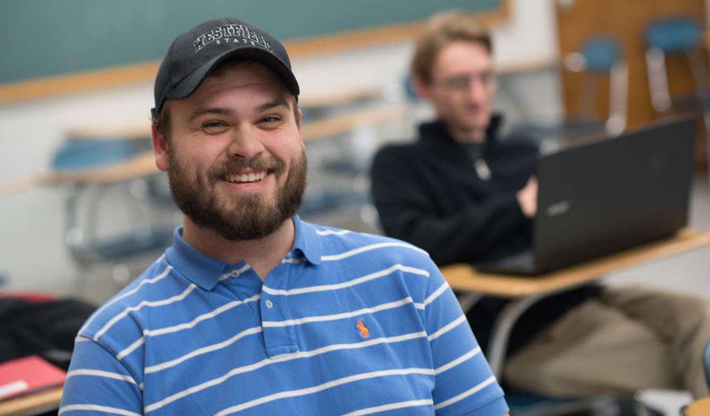 Male student, in ball cap, smiling at the camera