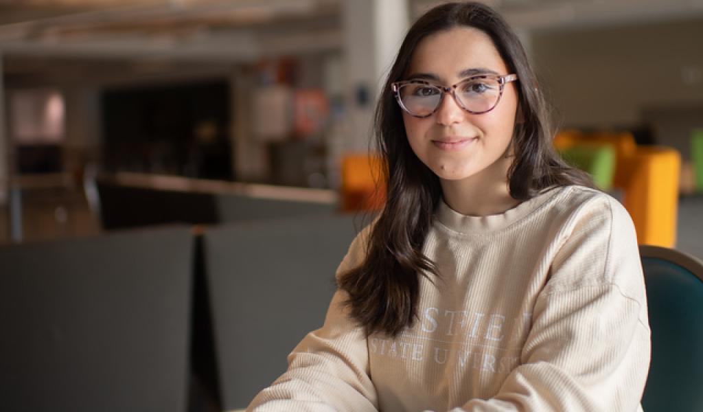 BSW student in library with long brown hair, glasses, and beige WSU sweatshirt